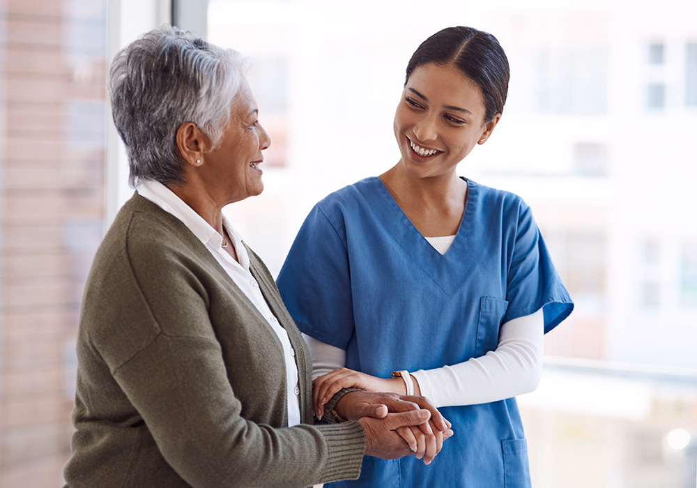 Nurse smiling and walking arm in arm with a female resident