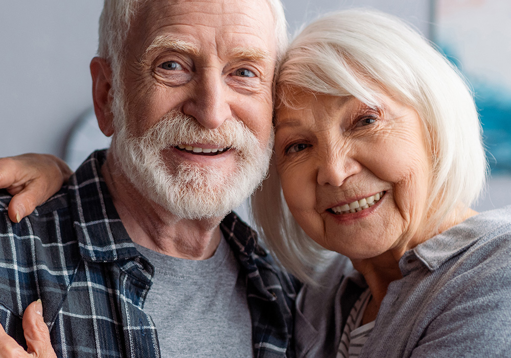 Smiling grey haired couple leaning their heads together